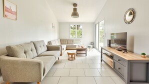 Una sala de estar moderna con un sofá, una mesa de centro, un televisor y un comedor.