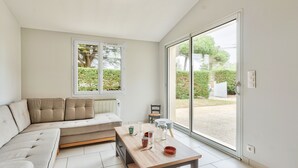 Una sala moderna con un sofá seccional, una mesa de centro de madera y un ventanal corredizo que da a un jardín.