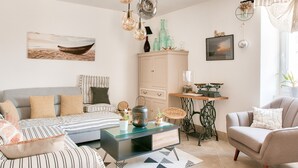 A living room with a sofa, armchair, and coffee table, a cabinet, and a hanging light fixture. - Stunning 4* Home for 6, Beach & Port Walkable (Le Guilvinec)