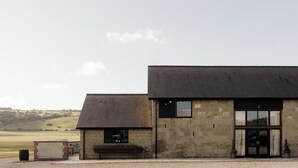 A building with a stone facade, a black roof, and a large window with curtains.
