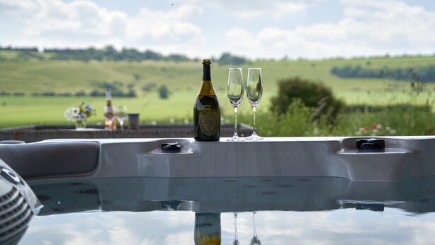 A table with a bottle and two glasses, set against a scenic outdoor view.