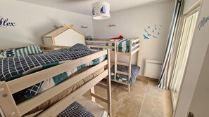 A bedroom with bunk beds, a desk, and a window.