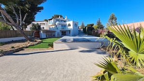 Une maison moderne à deux étages, dotée d’un toit plat, d’un mur de soutènement en pierre et d’une pelouse bien entretenue.