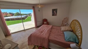 Une chambre à coucher avec un lit, une chaise, une fenêtre et une vue sur un jardin.