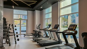 A gym with treadmills, elliptical machines, and weightlifting equipment. - HiGuests - Madison Residency (Dubai)