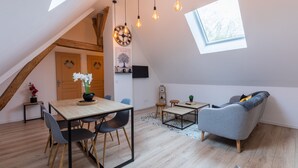 Een modern loft appartement met een eethoek, een grijze bank en een dakraam.