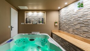 Een moderne badkamer met een bubbelbad, een raam met uitzicht en een stenen muur.