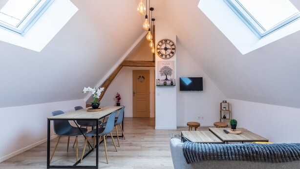Een modern loft met dakramen, een eethoek, een woongedeelte en een aan de muur bevestigde televisie.