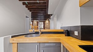 A kitchen with a wooden countertop, stainless steel appliances, and a stone accent wall. - Lucius, 1BR/1BA, 2 people (París)