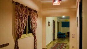 A hallway with patterned curtains, a patterned rug, and a blue couch in the background. - Jamila basement apartment (New Cairo)