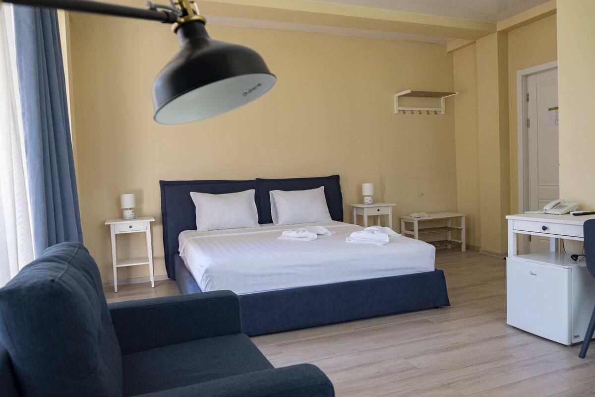 Une chambre d’hôtel comprenant un lit, des tables de chevet, un bureau, une chaise et une lampe.