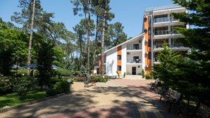 A multi-story building with balconies and a courtyard with benches and trees.