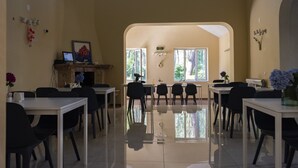 A spacious dining area with multiple tables and chairs, a fireplace, and large windows allowing natural light.