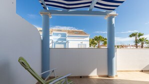 A covered outdoor seating area with a chair, a pergola, and a view of a building with a tiled roof. - 4 bedroom villa in condominium with swimming pool by AlgarveManta (9V4) (Manta Rota)