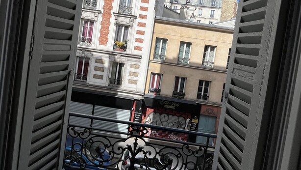 Vista desde un balcón con barandilla de metal, con vista a una calle con edificios.