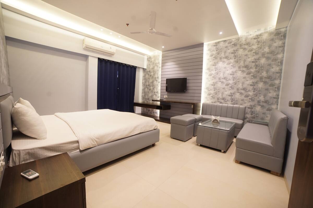 Une chambre moderne avec un lit, un canapé, une télévision et un ventilateur de plafond.