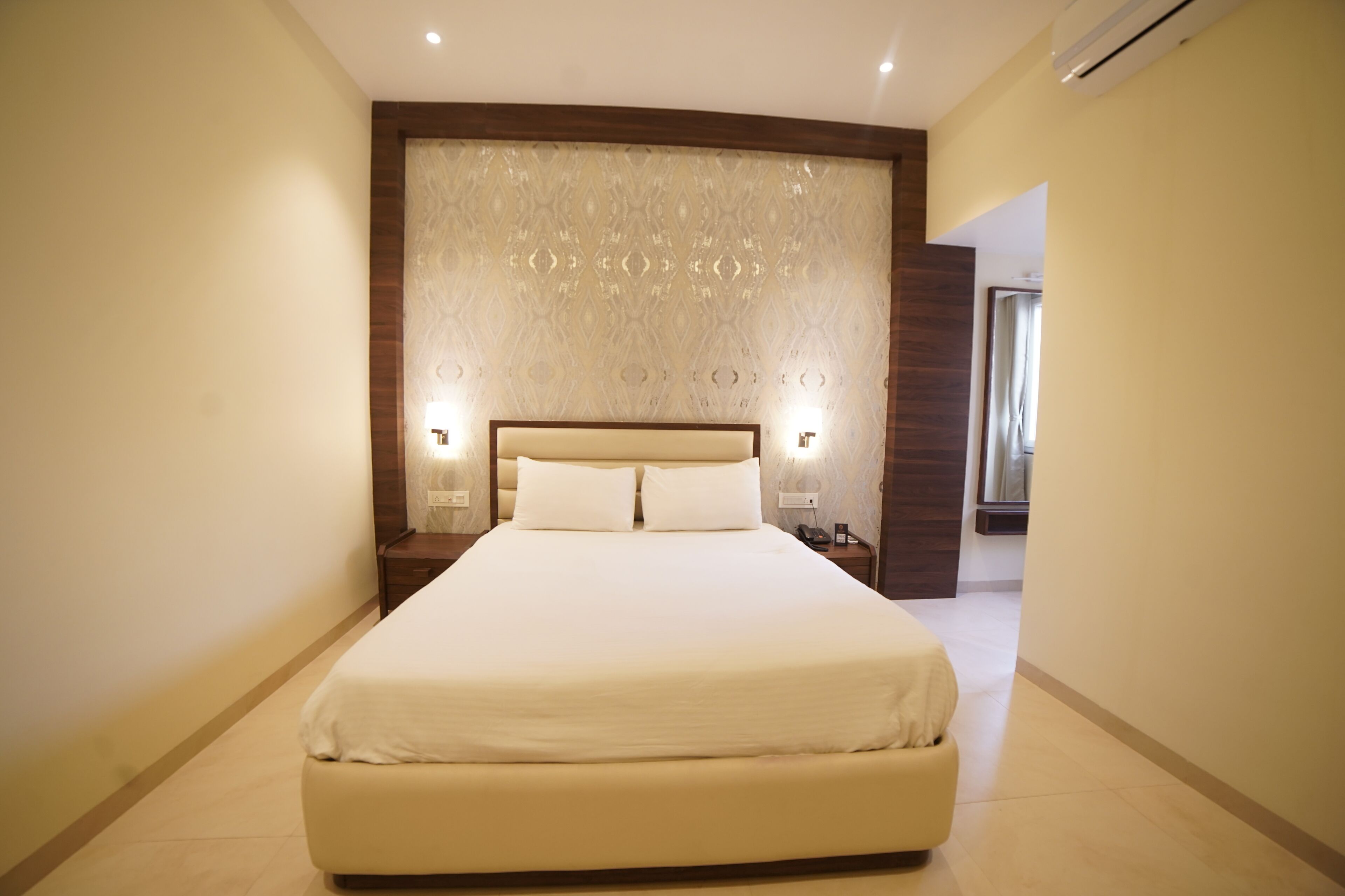 A large, neatly made bed with a wooden headboard and two bedside lamps.