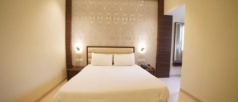 A large, neatly made bed with a wooden headboard and two bedside lamps.