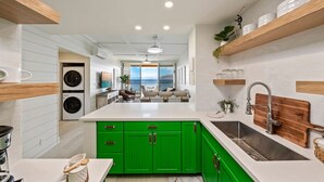 Cocina moderna con armarios verdes, una isla grande y vistas al área de estar.