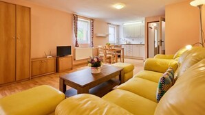 A compact living space with a yellow sofa, a wooden dining table, and a kitchenette in the background. - U Šustrů by Interhome (Horní Maršov/Pec pod Sněžkou)