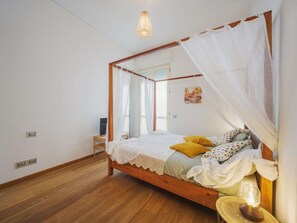 Un dormitorio con una cama de madera con dosel, ropa de cama blanca y un dosel.