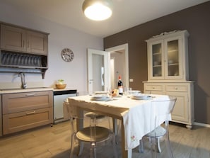 Una cucina con un tavolo da pranzo per quattro persone, una sveglia e una bottiglia di vino.