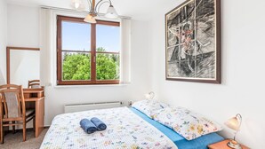 A bedroom with a bed, a desk, and a chair. There is a window with a view of trees and a painting on the wall. - Harrachov Lookout by Interhome (Harrachov)