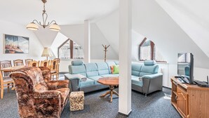 A spacious loft with high ceilings, a dining area, a living room with a sofa and armchairs, and a television on a wooden cabinet. - Harrachov Lookout by Interhome (Harrachov)