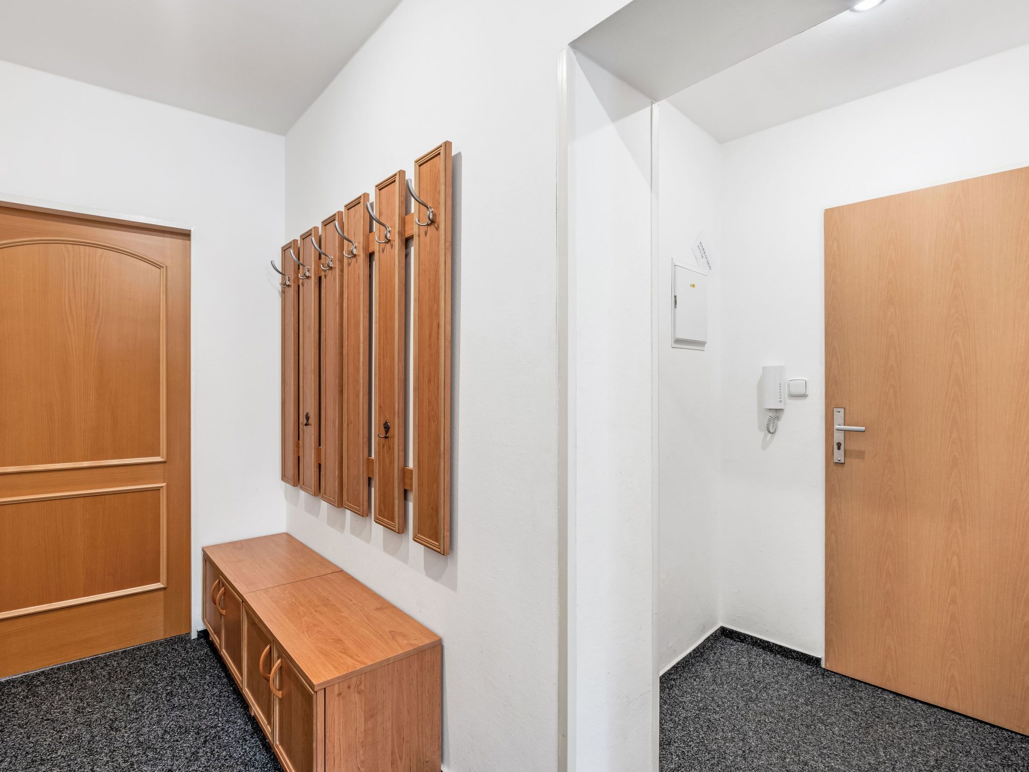A hallway with a wooden bench, a coat rack, and a door.