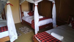 Une chambre avec trois lits, chacun surmonté d’un dais et agrémenté d’un tapis à motifs zébrés.