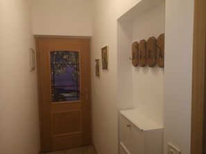 A hallway with a wooden door featuring a stained glass window, a white cabinet, and a wall-mounted coat rack. - Moja Ane (Razanac)