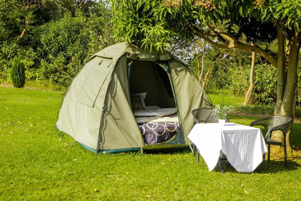 Una carpa con una cama en su interior, una mesa con mantel blanco y sillas.