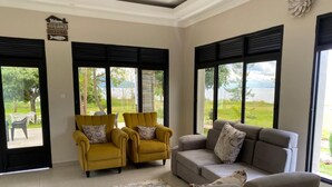 Una sala de estar con dos sillones amarillos, un sofá gris y vistas a un lago.