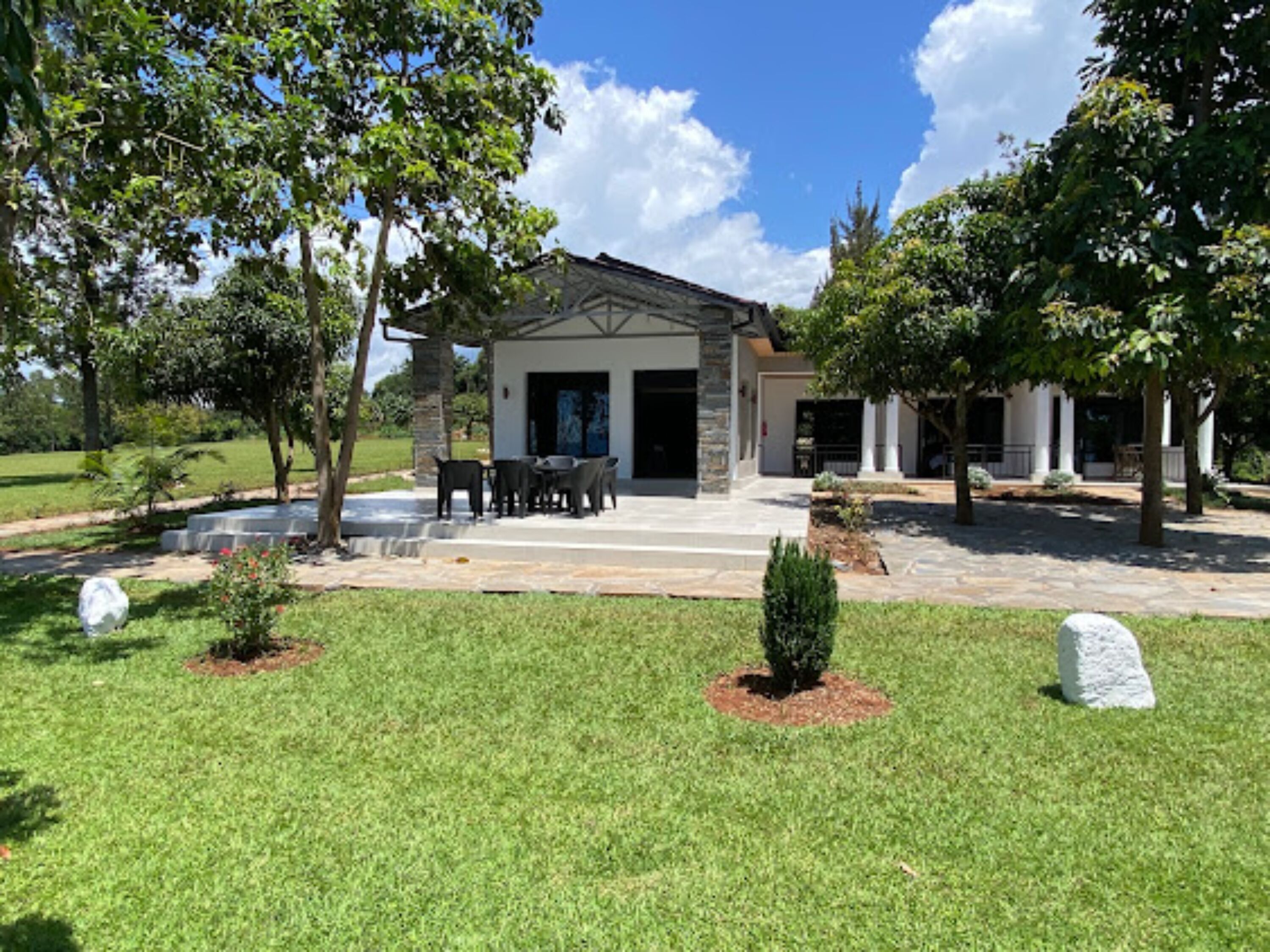 A modern house with a covered patio, stone exterior, and a well-maintained lawn.