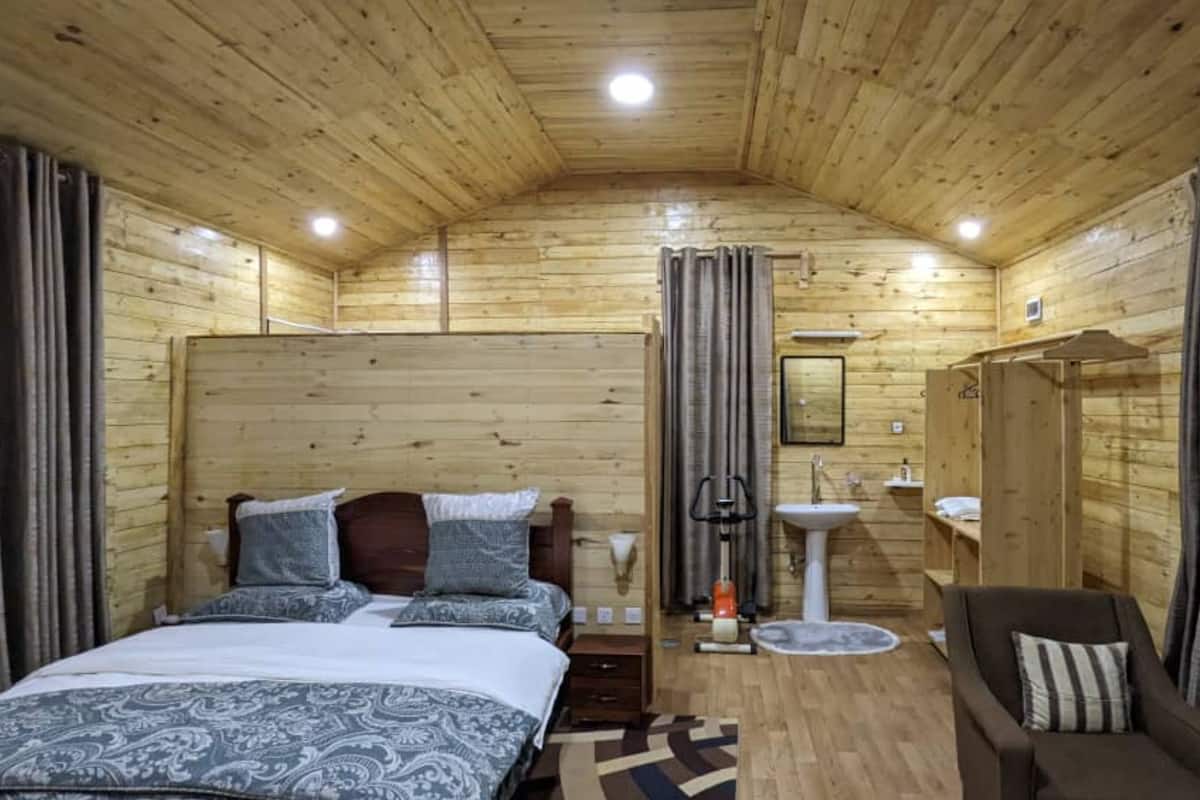 Une chambre dans une cabane en bois, avec un lit, une chaise, un lavabo et un miroir.