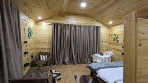 Una acogedora habitación de cabaña de madera con una cama, una mesita, una silla y una cortina.
