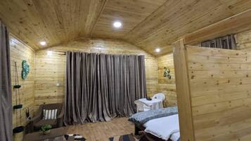 Una camera in legno con un letto, un tavolino, una sedia e una tenda.