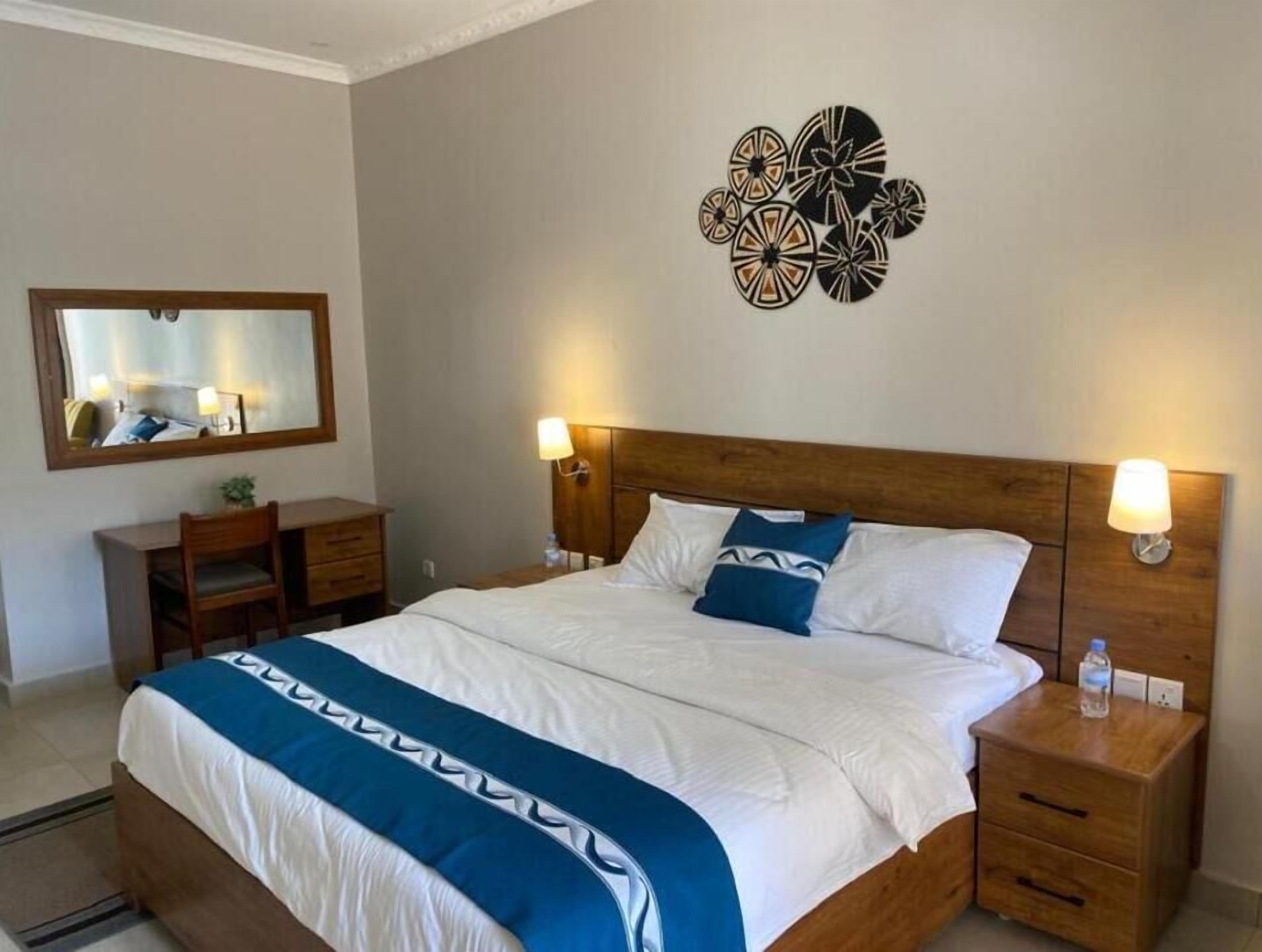 Una habitación de hotel con cama, mesitas de noche, un espejo y decoración en las paredes.