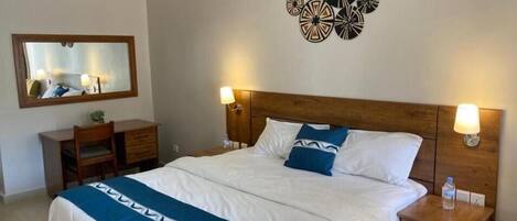 Una habitación de hotel con cama, mesitas de noche, un espejo y decoración en las paredes.