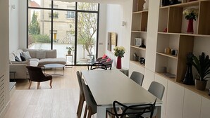 Ein zeitgemäßer Wohnraum mit Essbereich, einer Couch und einem Bücherregal.