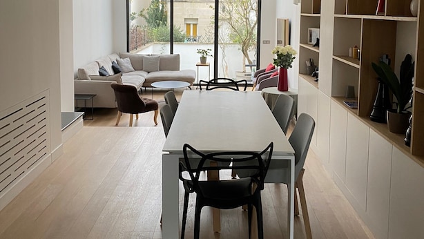 Ein modernes Wohnzimmer mit Essbereich, großen Fenstern und einer Bücherwand.