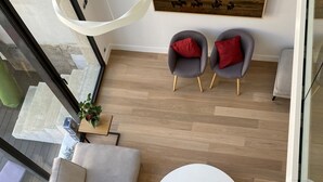 Ein modernes Wohnzimmer mit einem Ecksofa, einem runden Couchtisch und zwei grauen Sesseln mit roten Kissen.