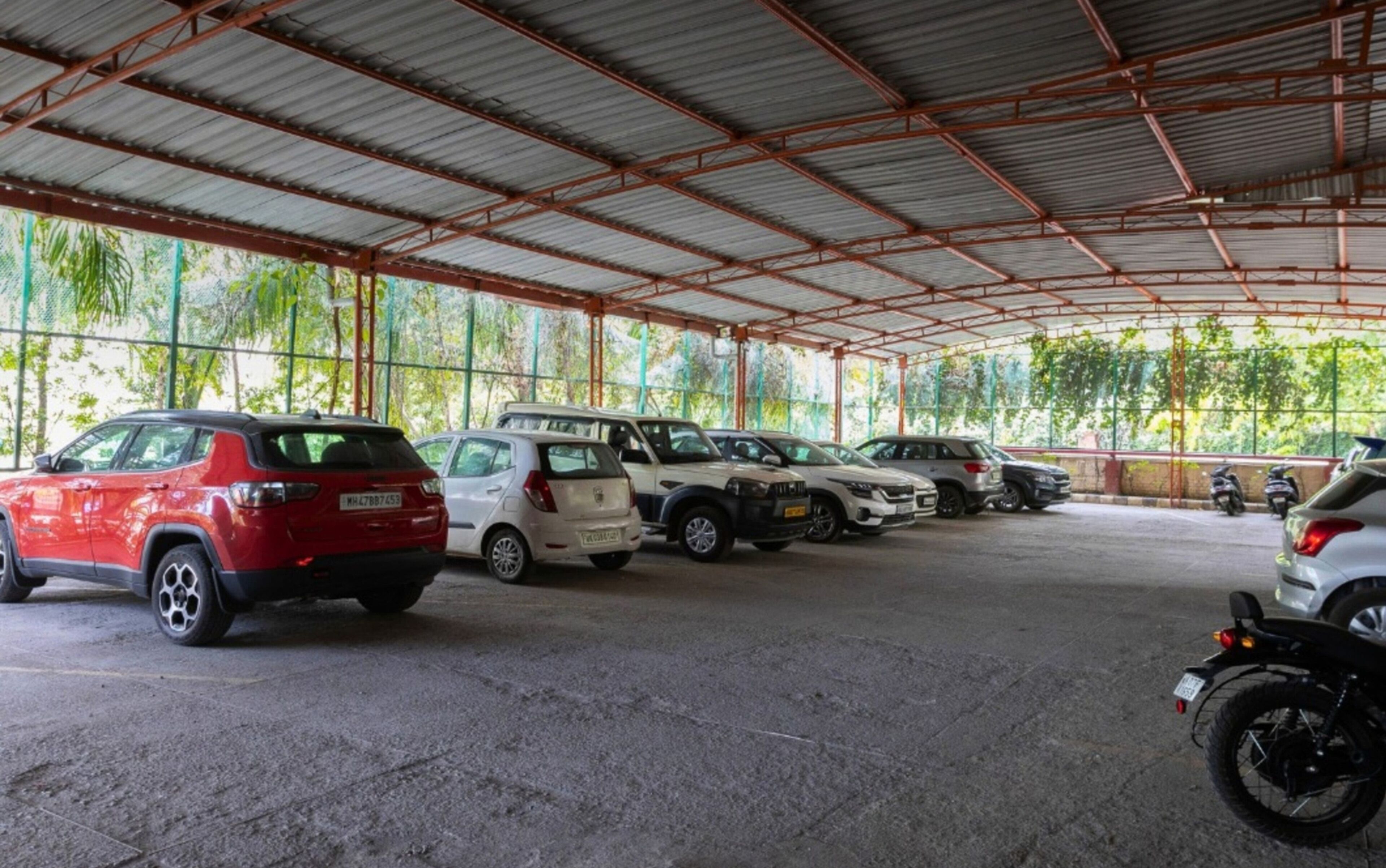 A covered parking area with multiple cars and motorcycles.