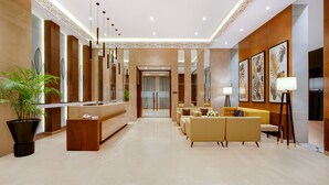 Un vestíbulo moderno con mostrador de recepción, zona de estar y elementos decorativos.