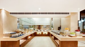 Un vestíbulo de hotel amplio y moderno, con un mostrador de recepción central, un gran muro de cristal que ofrece vistas del interior y un diseño limpio y minimalista.