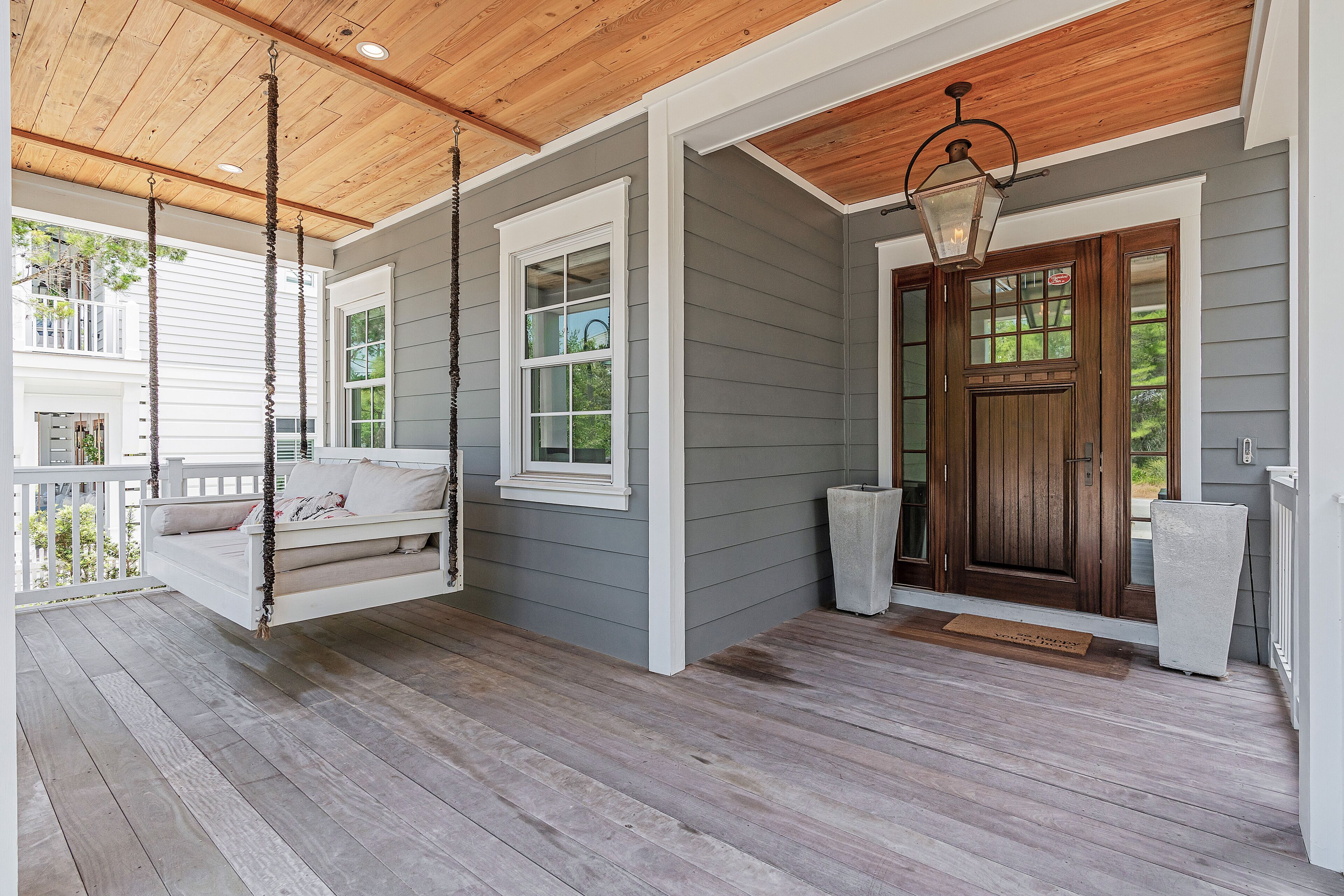 A porch with a swing, a wooden door, and a white mailbox.