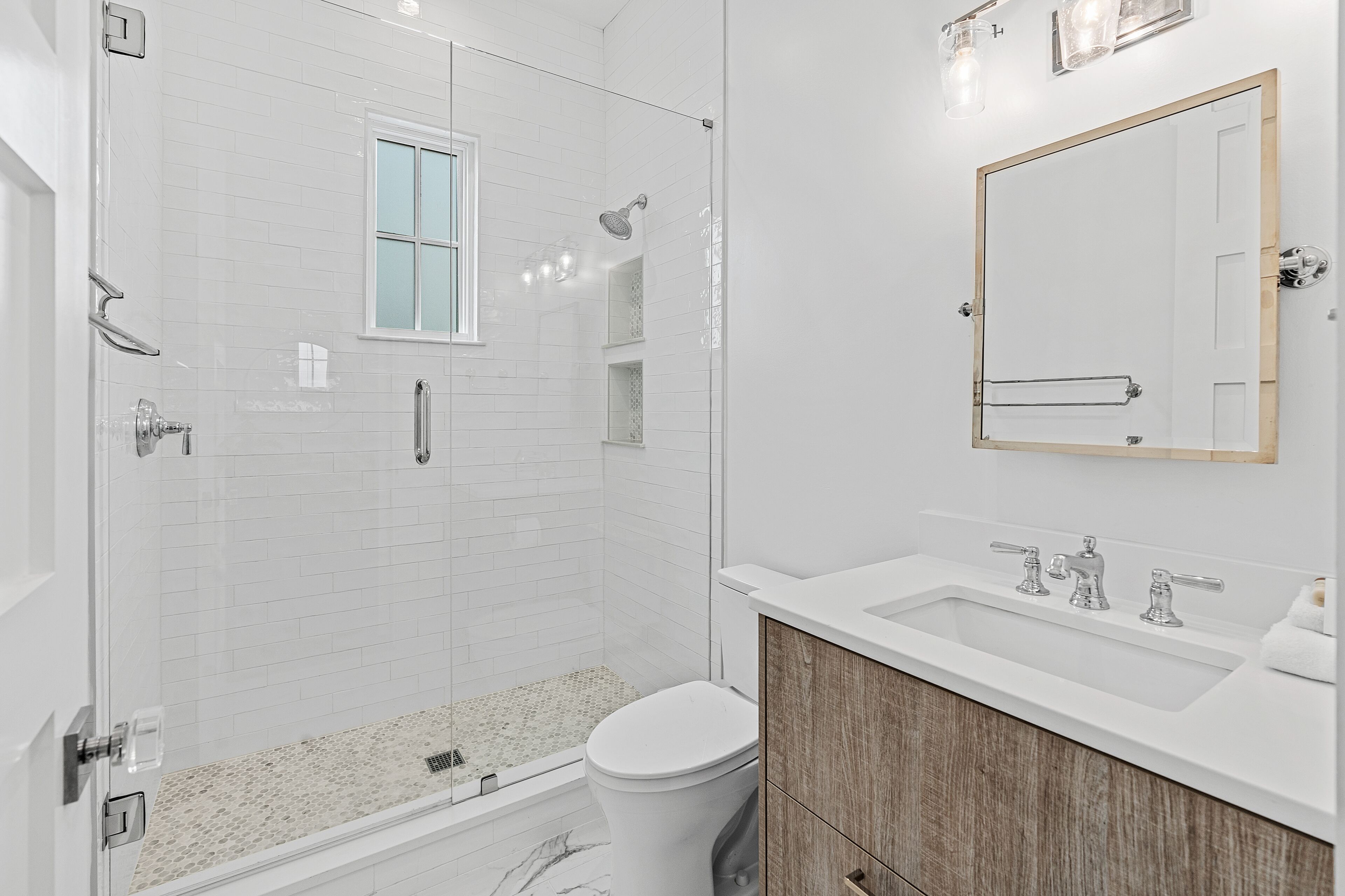 Une salle de bain moderne avec une douche à parois de verre, des toilettes, un lavabo et un miroir.
