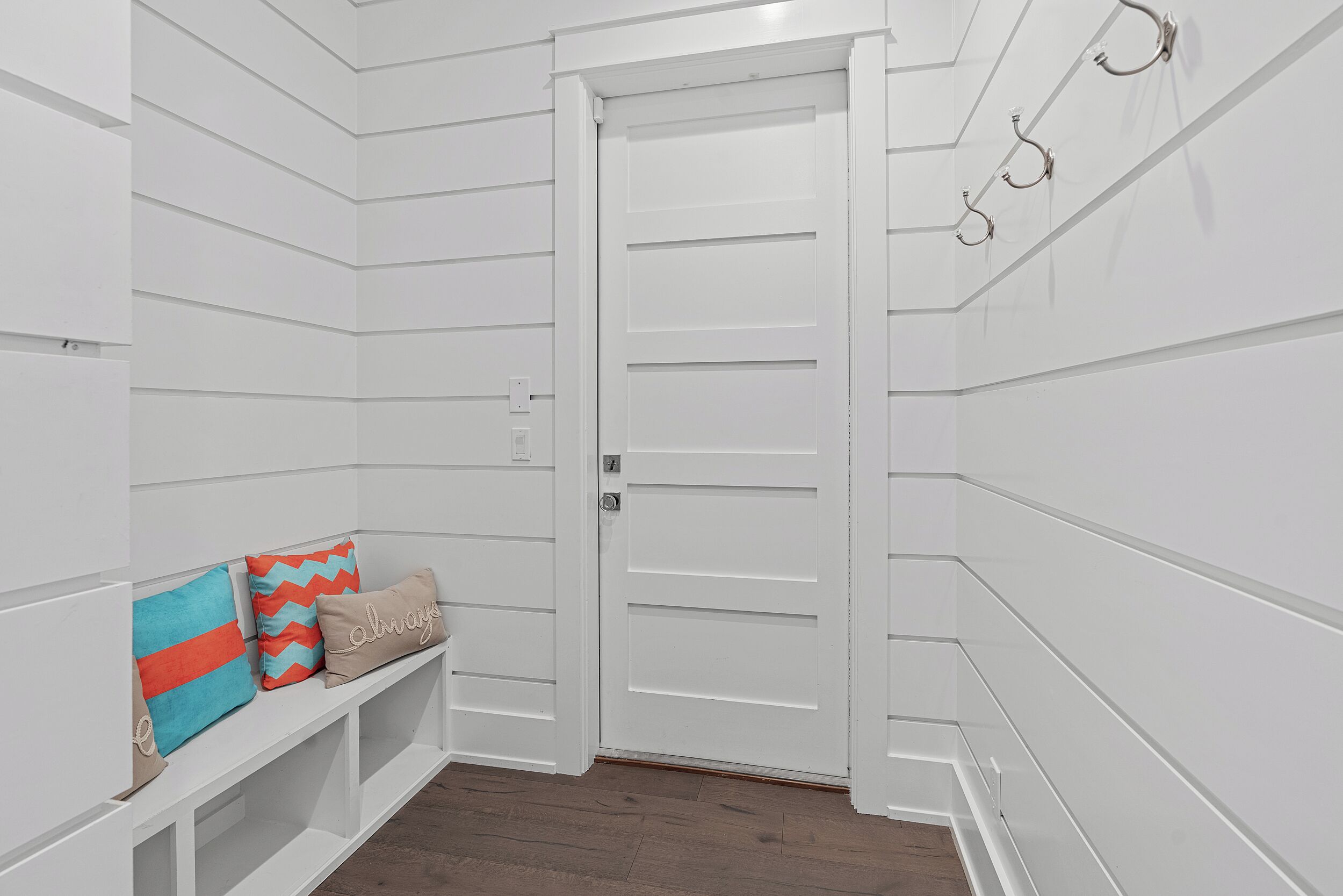 A white hallway with a bench and a door.