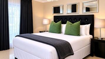 A hotel room with a large bed, two bedside tables, a chandelier, and three mirrors on the wall.