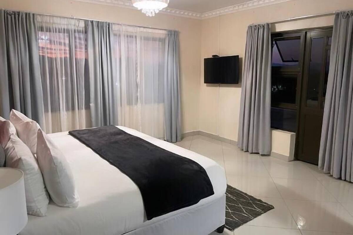 Una habitación de hotel con una cama, televisión y puerta corrediza a un balcón.